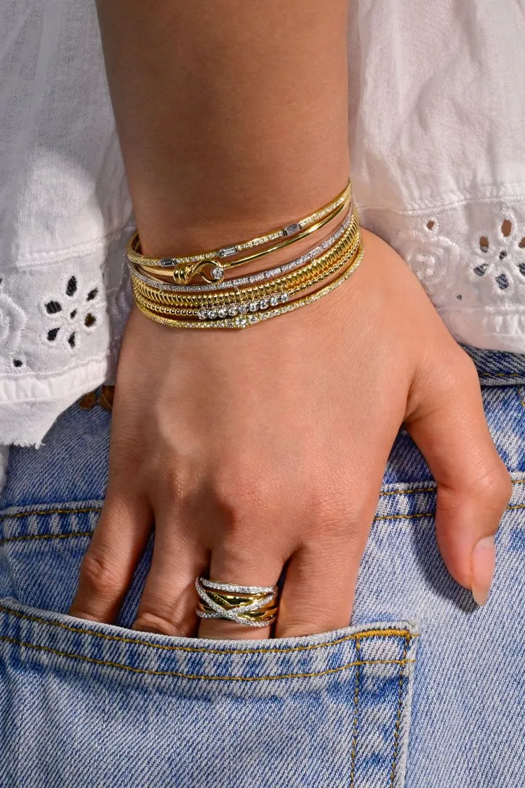 A hand with multiple gold and silver bracelets and a ring, showcasing fine jewelry from Sterling Jewelers in Wethersfield.