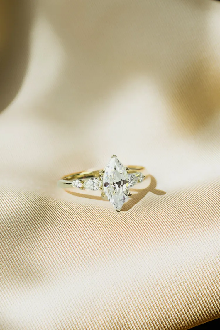 A hand adorned with a pear-shaped diamond engagement ring and a sparkling band, showcasing fine jewelry elegance.