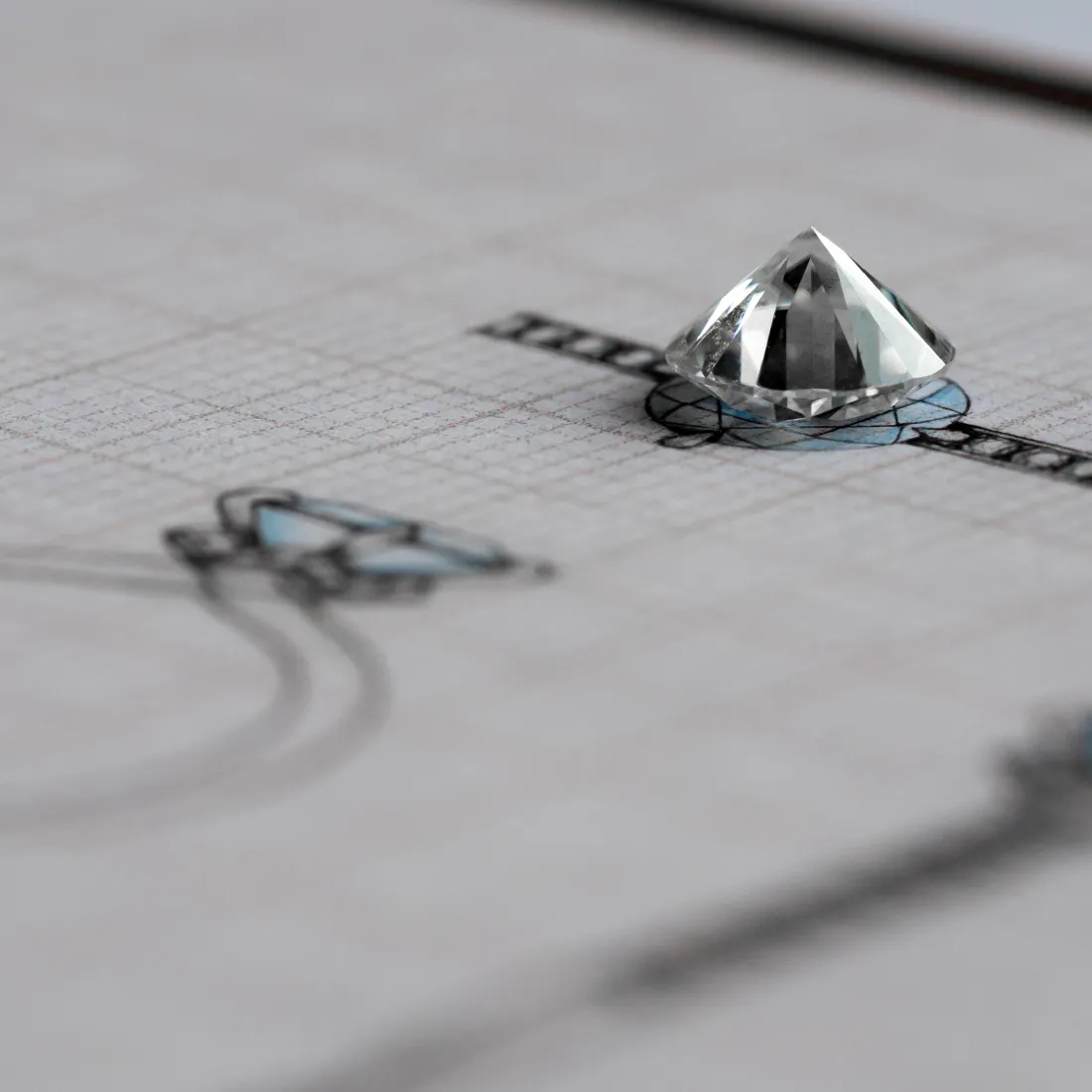 A diamond sits atop a design sketch for jewelry, showcasing the custom design process.