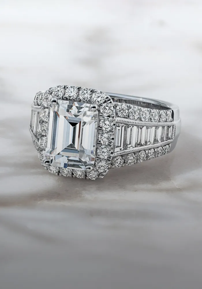 Elegant diamond engagement ring with an emerald-cut center stone, surrounded by smaller diamonds.