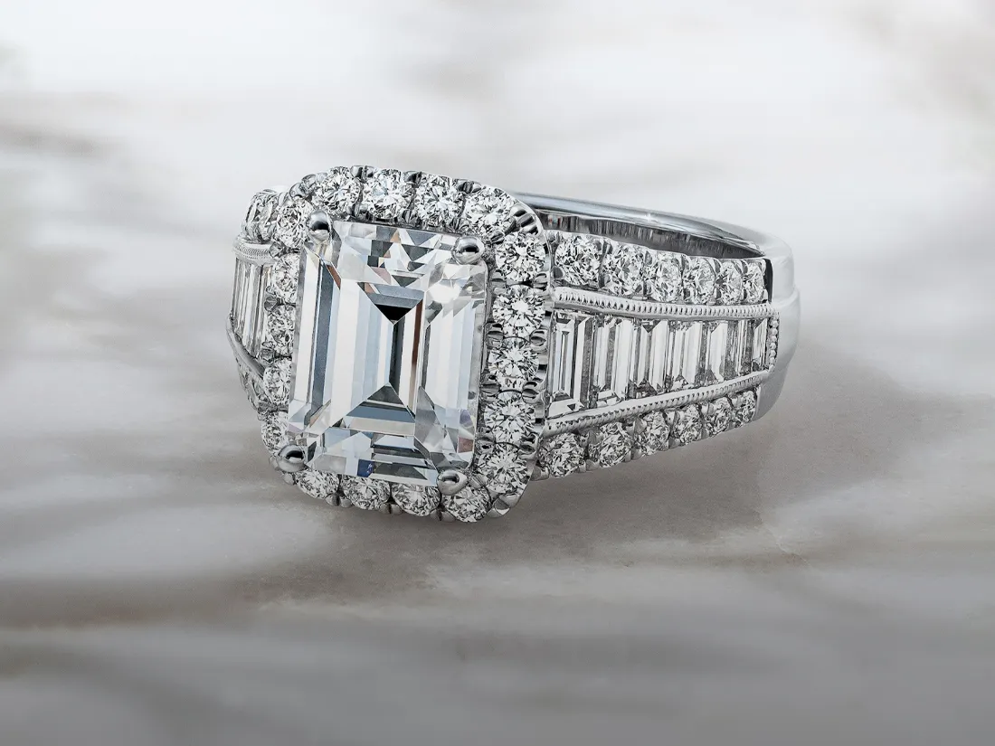 Elegant diamond engagement ring with an emerald-cut center stone, surrounded by smaller diamonds.