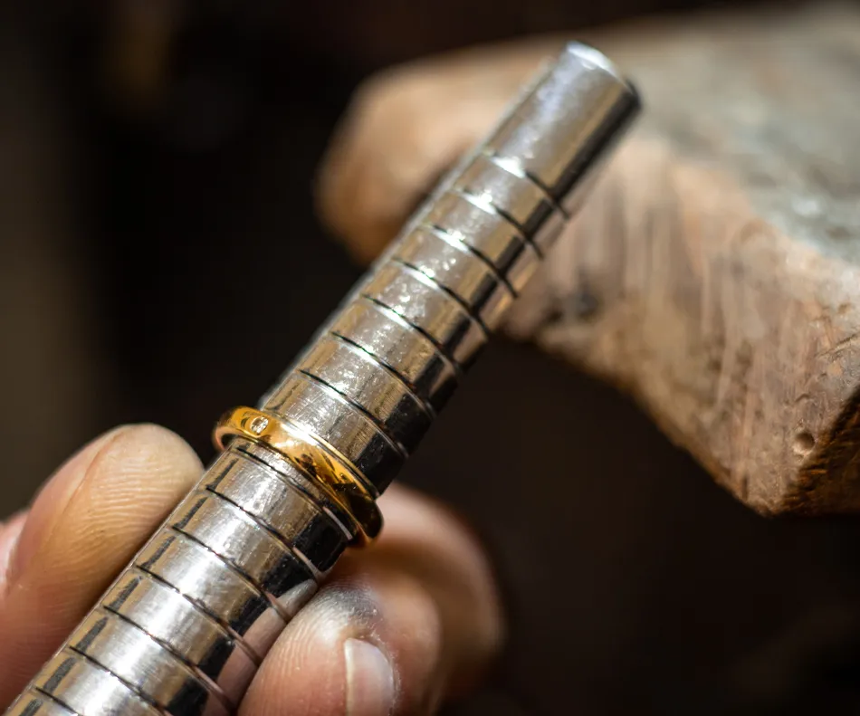 A gold ring on a metal mandrel, showcasing jewelry craftsmanship at Sterling Jewelers in Wethersfield.