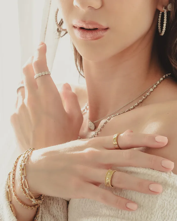 Close-up of a woman showcasing elegant gold and diamond jewelry.