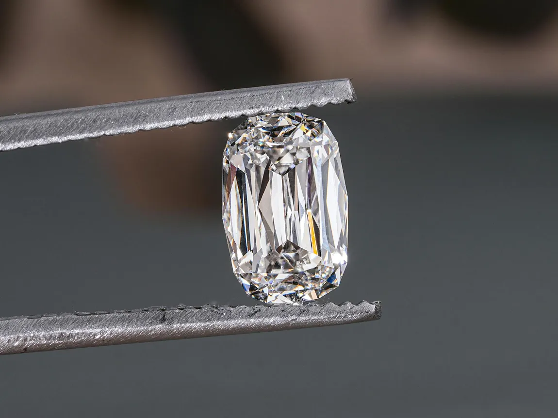 Close-up of a sparkling diamond held by tweezers, showcasing its clarity and brilliance.