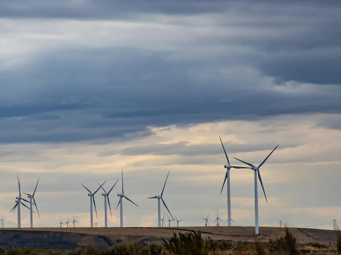 Wind turbines against a cloudy sky, symbolizing renewable energy.