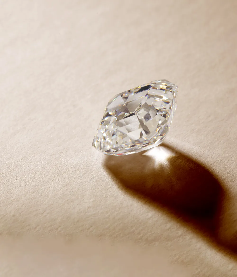 A sparkling diamond on a soft surface, casting a shadow, representing fine jewelry from Sierra Moon in Auburn.