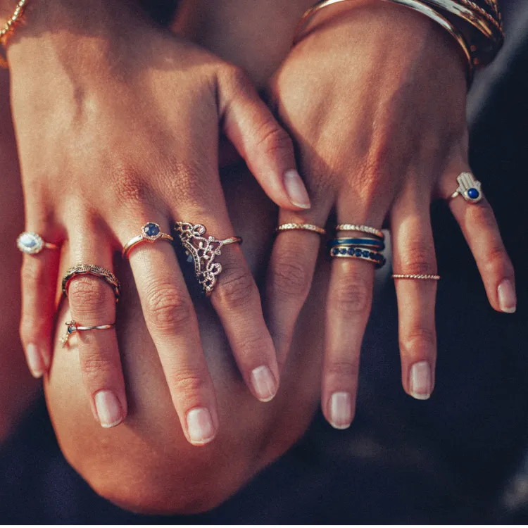 Hands adorned with multiple rings featuring gemstones and intricate designs. Click to Shop Now at Simones Jewelry.