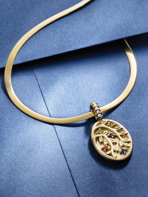 Gold pendant necklace with colorful gemstones on a blue background. Click to Shop Now at Simones Jewelry, LLC.