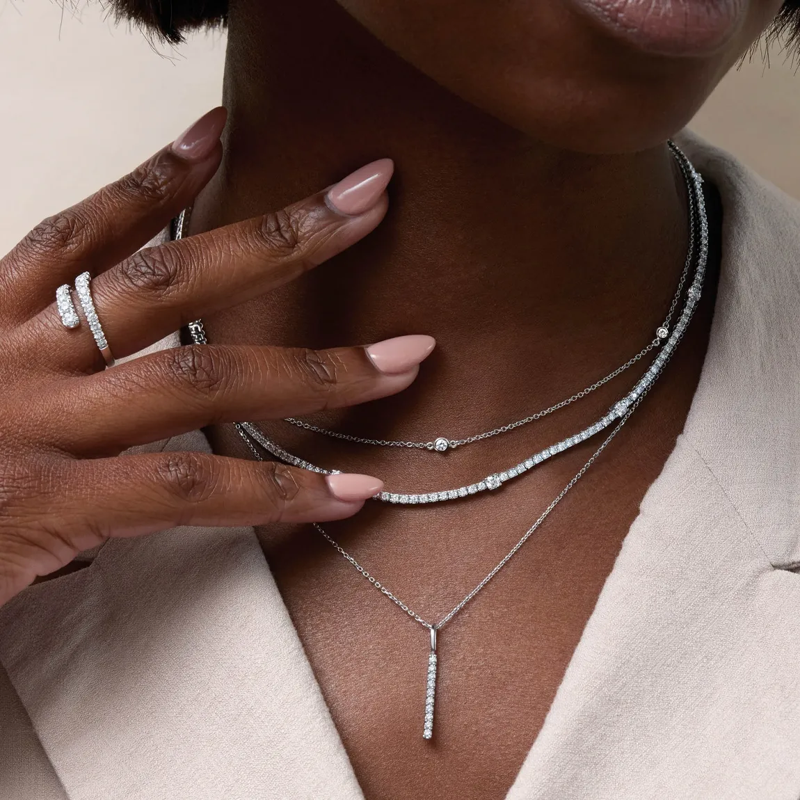 Elegant silver necklaces and rings adorned on a model's hand, showcasing fine jewelry from Simones Jewelry, LLC.