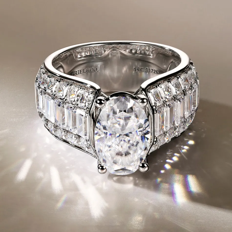 Elegant oval diamond ring with baguette and round cut diamonds, set in a 14K white gold band. Visit Synder Jewelers.