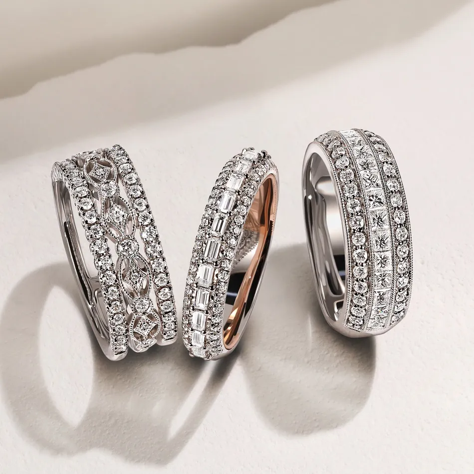 A hand placing a diamond engagement ring on another hand, surrounded by white roses.