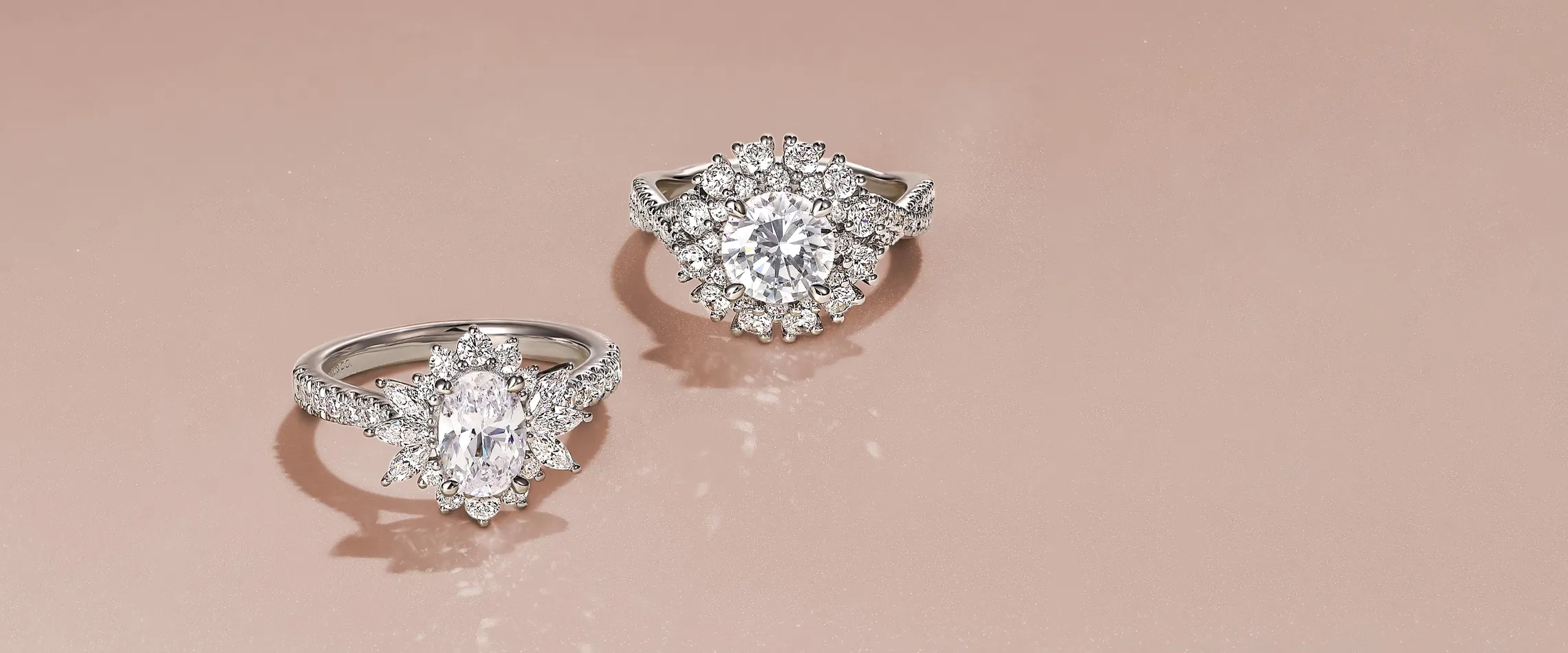 Two stunning diamond engagement rings on a soft pink background. Click to shop engagement rings at Snyder Jewelers.