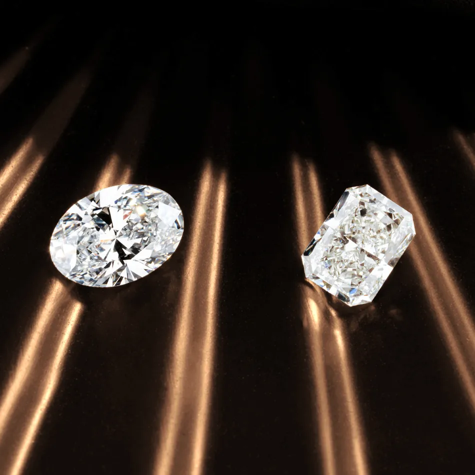 Two sparkling diamonds, one oval and one rectangular, displayed against a dark background with light reflections.
