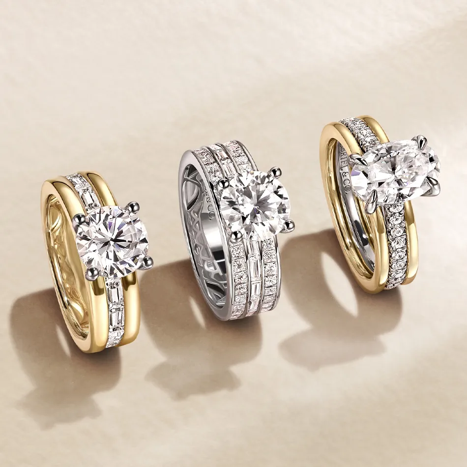 Three elegant engagement rings featuring round diamonds, set in yellow and white gold bands with sparkling accents.