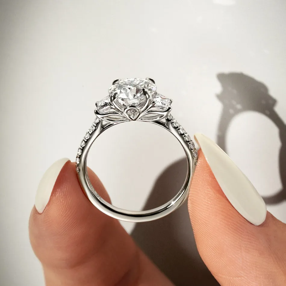 Elegant diamond engagement ring held between fingers, showcasing intricate design and sparkle. Visit Synder Jewelers for more.