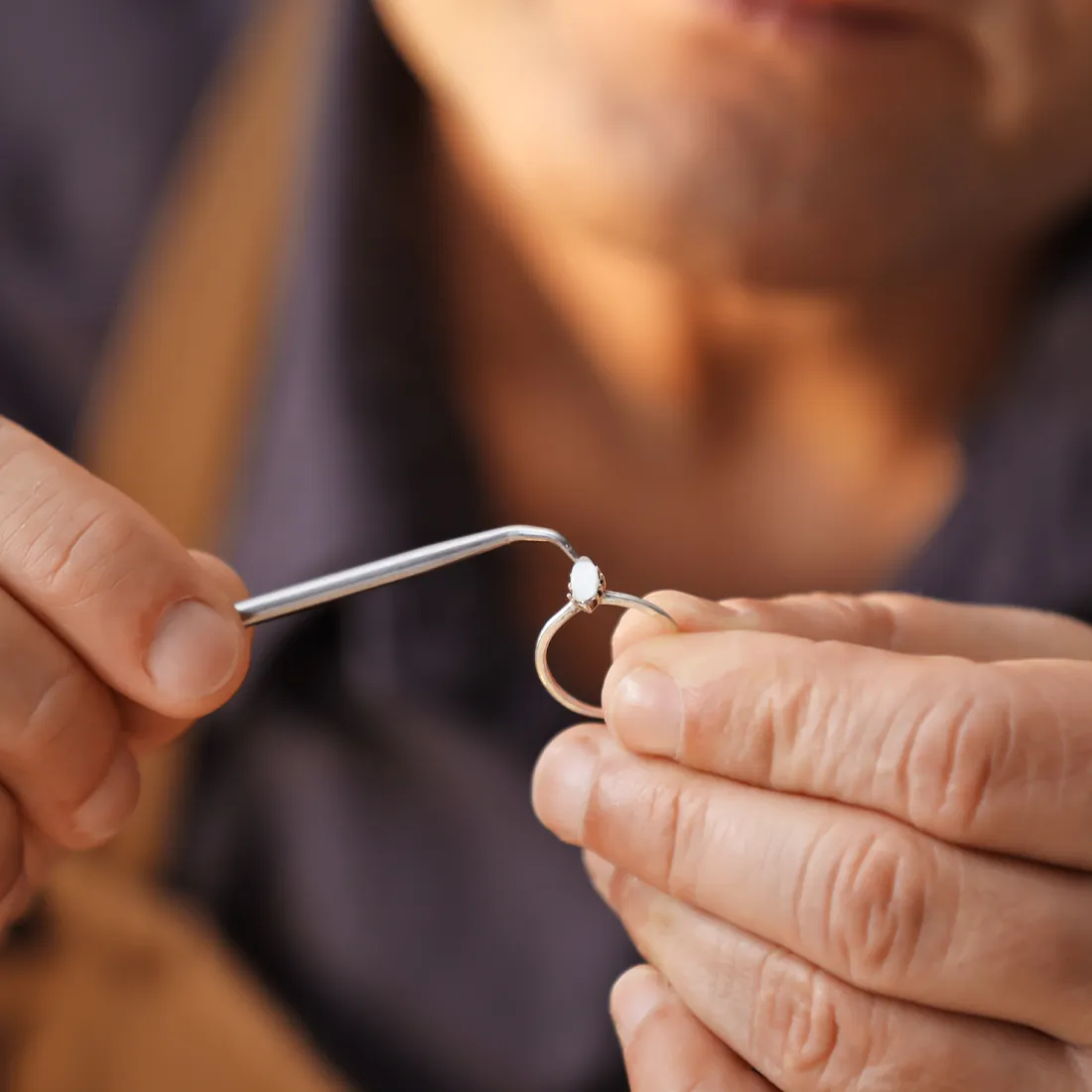 Jeweler using tweezers to set a gemstone in a ring, showcasing the finishing process at Synder Jewelers in Longmont.