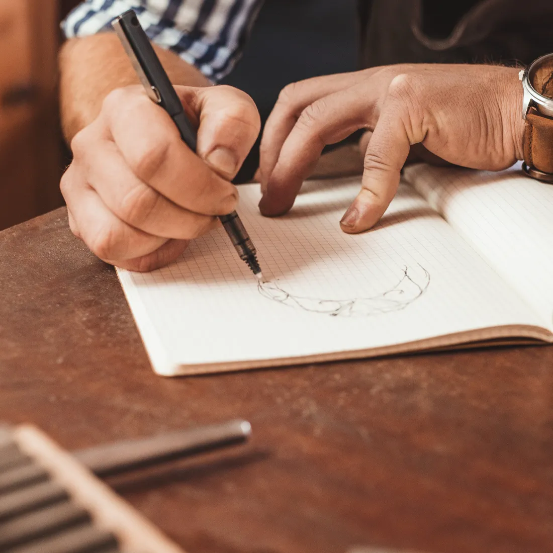 A hand sketching a design in a notebook, showcasing the creative process at Synder Jewelers in Longmont.
