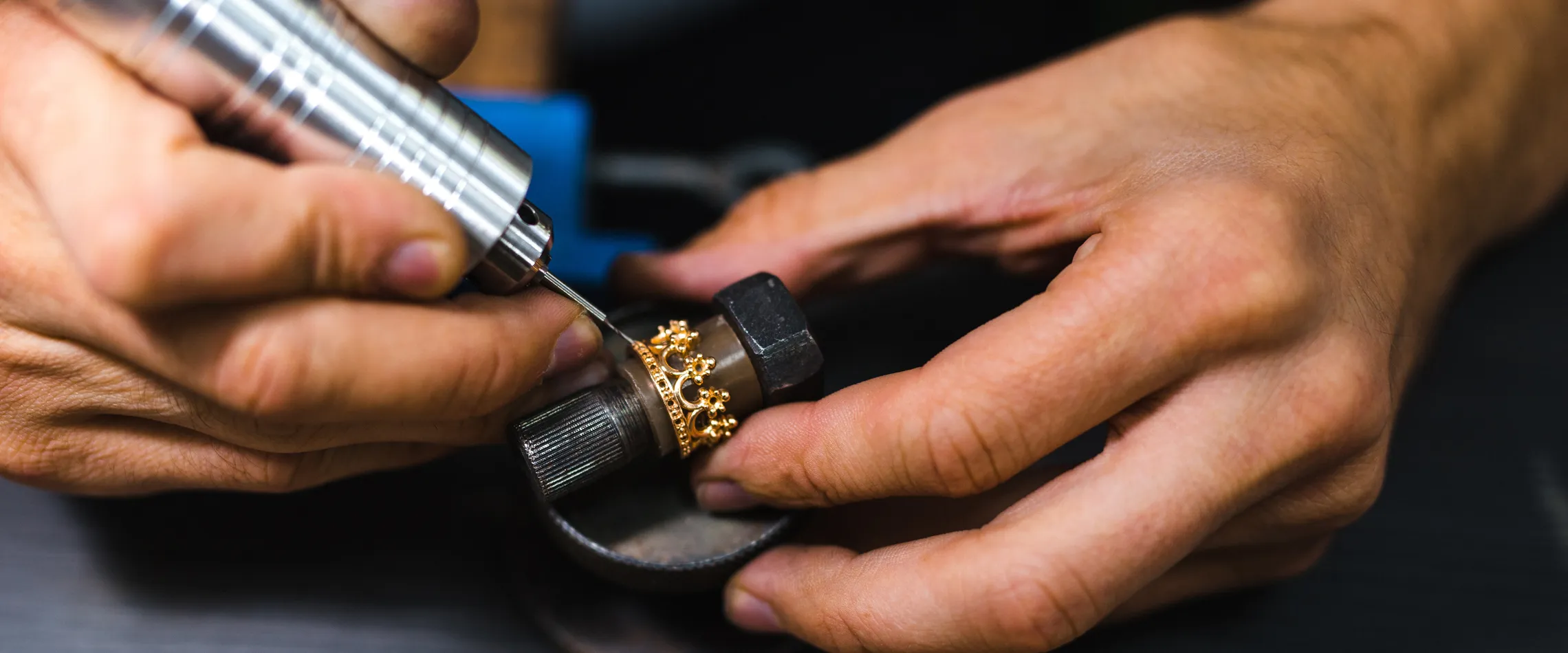 Jeweler using a rotary tool to craft a custom gold ring with floral design at Synder Jewelers in Longmont.
