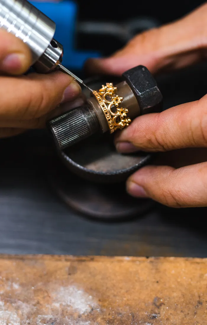Jeweler using a rotary tool to craft a custom gold ring with floral design at Synder Jewelers in Longmont.