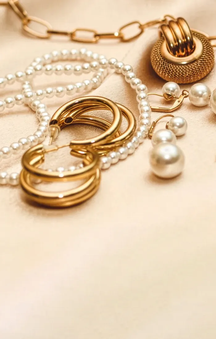 Elegant assortment of gold and pearl jewelry pieces on a soft fabric background.