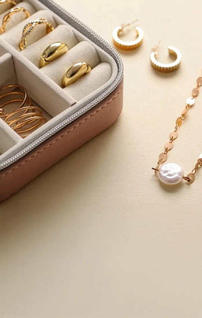 Gold jewelry including rings, earrings, and a pearl necklace in a display box. Visit Synder Jewelers for custom pieces.