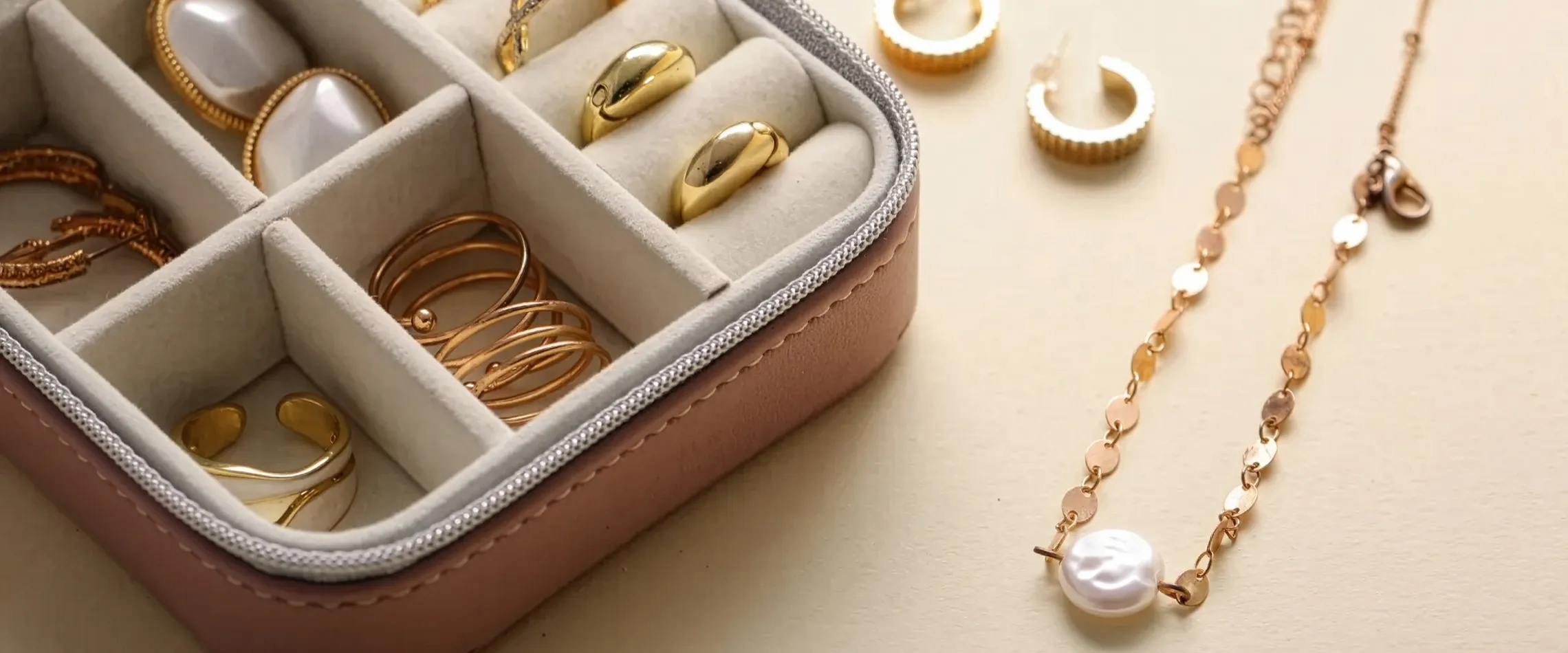 Gold jewelry including rings, earrings, and a pearl necklace in a display box. Visit Synder Jewelers for custom pieces.