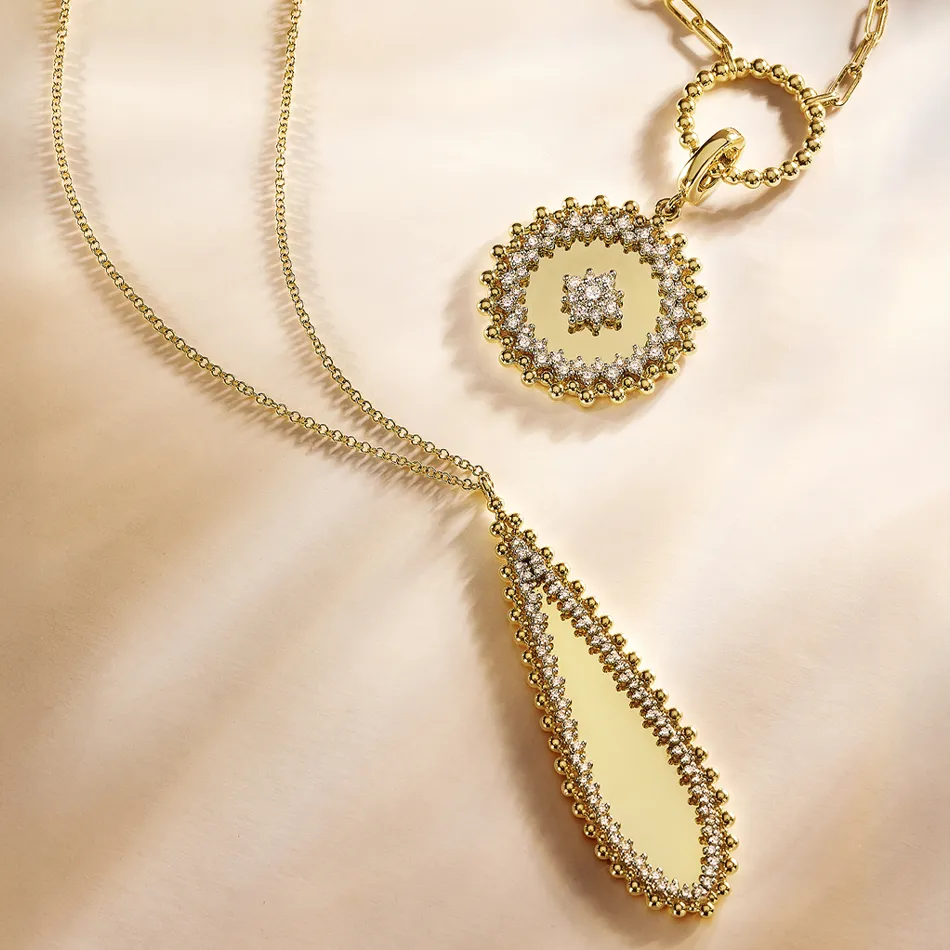 Elegant gold necklace featuring a teardrop pendant and a circular charm, adorned with sparkling stones. Visit Synder Jewelers.