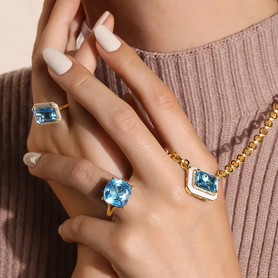 Close-up of hands wearing blue gemstone rings and a necklace, showcasing elegant jewelry from Synder Jewelers in Longmont.