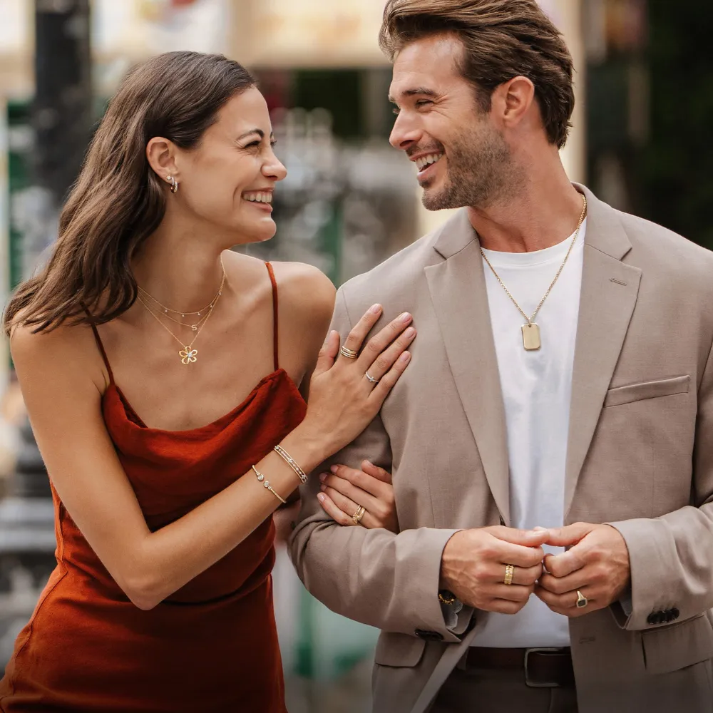 Couple in fine attire wearing Gabriel & Co. necklaces, earrings, and stacking rings &mdash; anniversary gifts from SVS Fine Jewelry Oceanside Long Island