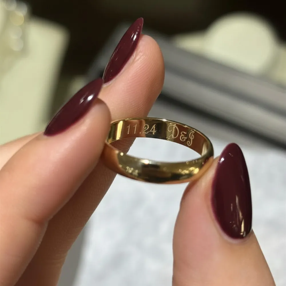 Yellow gold wedding band with date 11.24 and initials D and J engraved inside the band