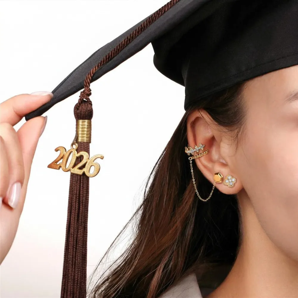 Female graduate in cap with 2026 tassel wearing layered SVS gold earring stack including ear cuff and studs &mdash; graduation jewelry gifts at SVS Fine Jewelry Long Island