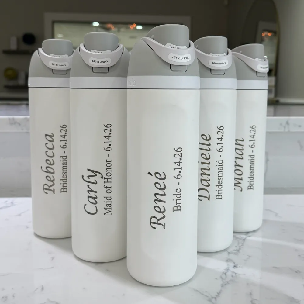 Five white insulated water bottles standing in a row, each engraved with a first name in script above the wearer's role in the wedding party