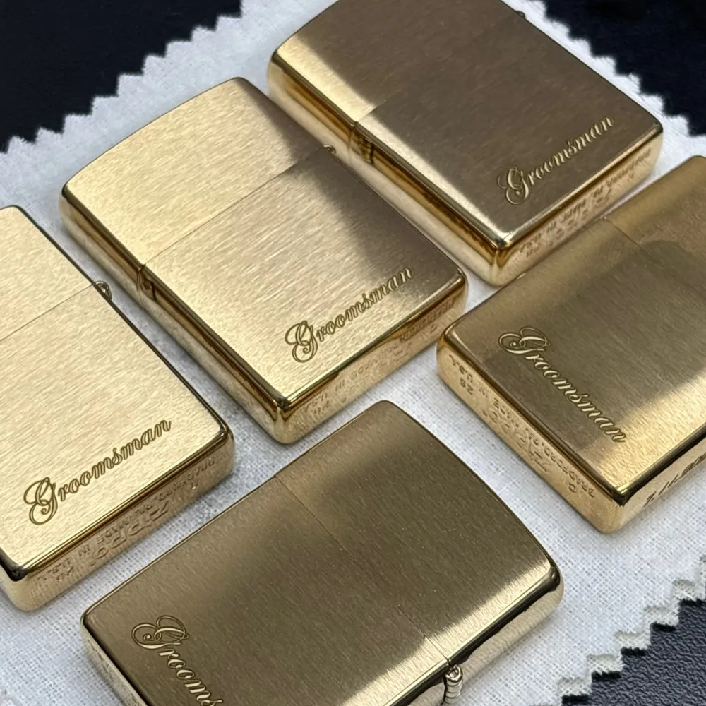 Five brass Zippo lighters arranged on a table, each engraved with script lettering