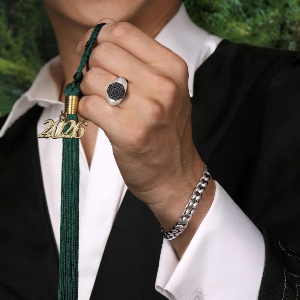 Male graduate in cap and gown holding 2026 tassel wearing SVS black diamond signet ring and silver Cuban chain bracelet &mdash; graduation jewelry gifts at SVS Fine Jewelry Long Island