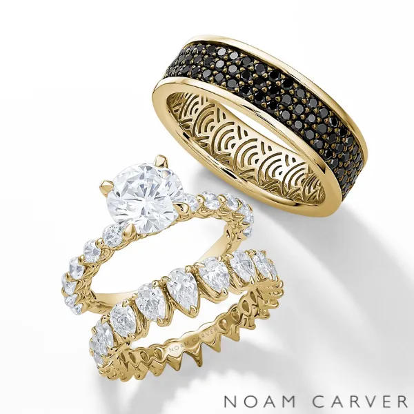Noam Carver matching wedding bands — men's yellow gold band with black diamond inlay and women's yellow gold diamond eternity