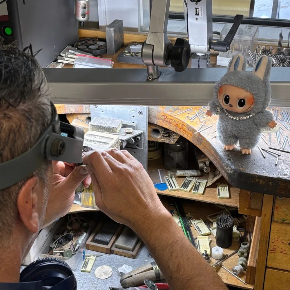 Oscar H., SVS Master Setter, working at the bench with a Labubu plush keeping watch