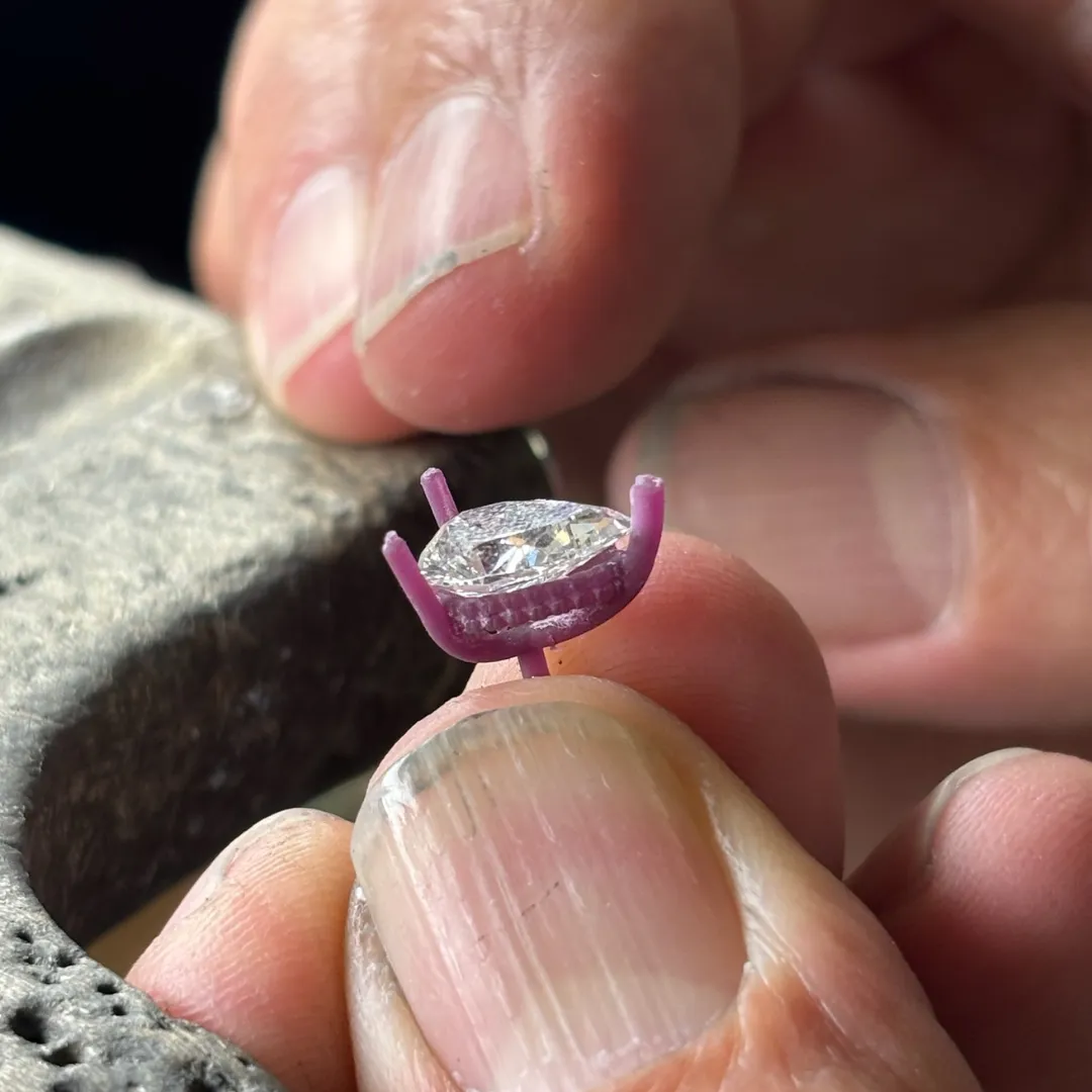 The same pear shaped diamond seated in a 3D printed wax model of its new setting with an under halo, held at the SVS Fine Jewelry bench