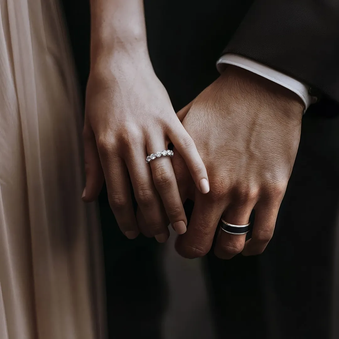 Couple wearing his and hers wedding bands — diamond eternity band and men's black inlay band — SVS Fine Jewelry Oceanside Long Island