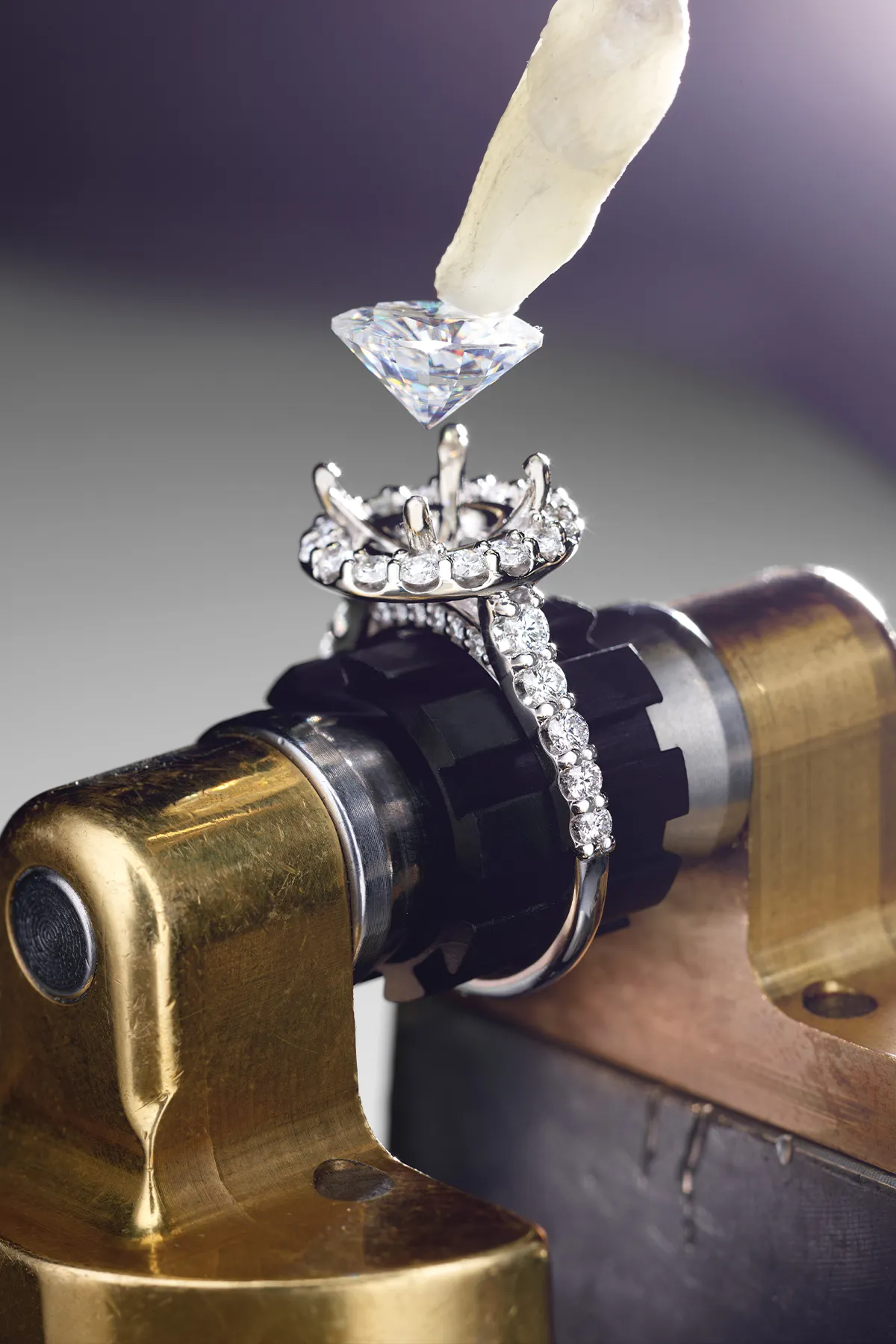 A diamond being set into a ring with a jeweler's tool.