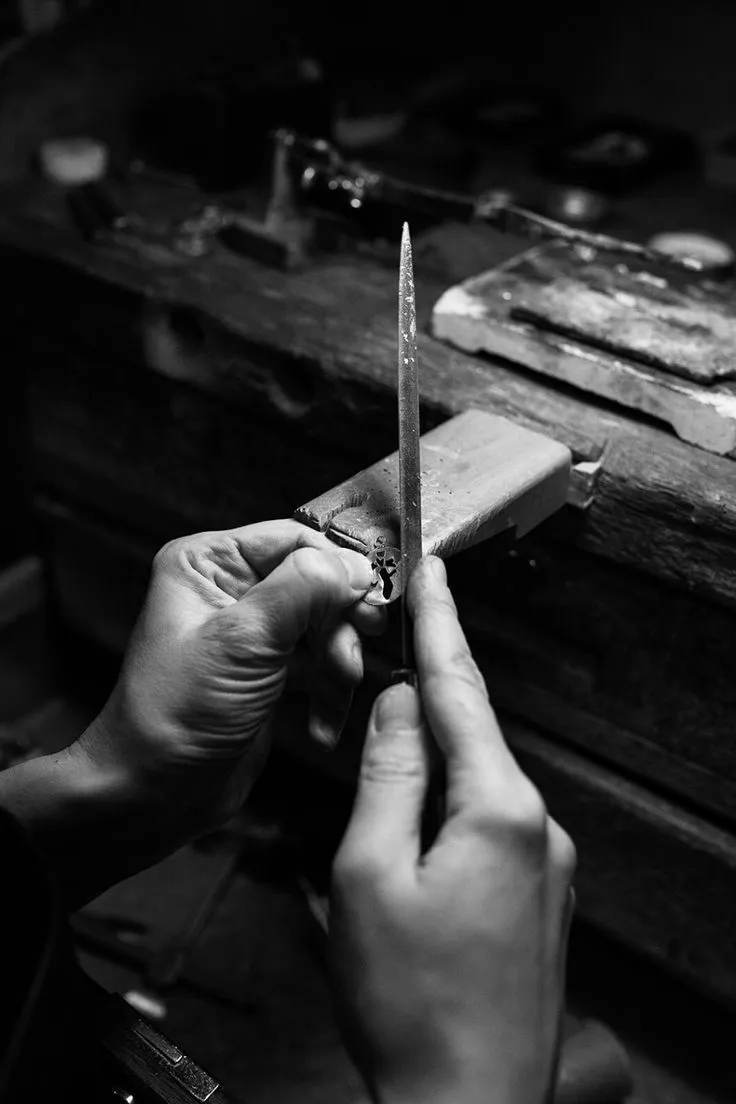 A jeweler delicately places a diamond in a silver ring, showcasing fine craftsmanship.