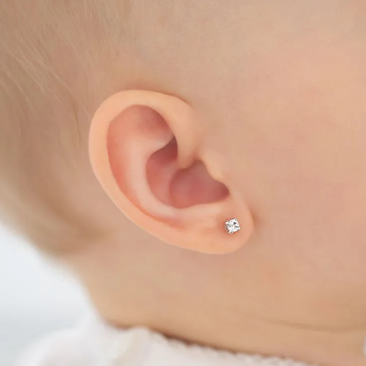 Close-up of a child's ear with a sparkling diamond earring.