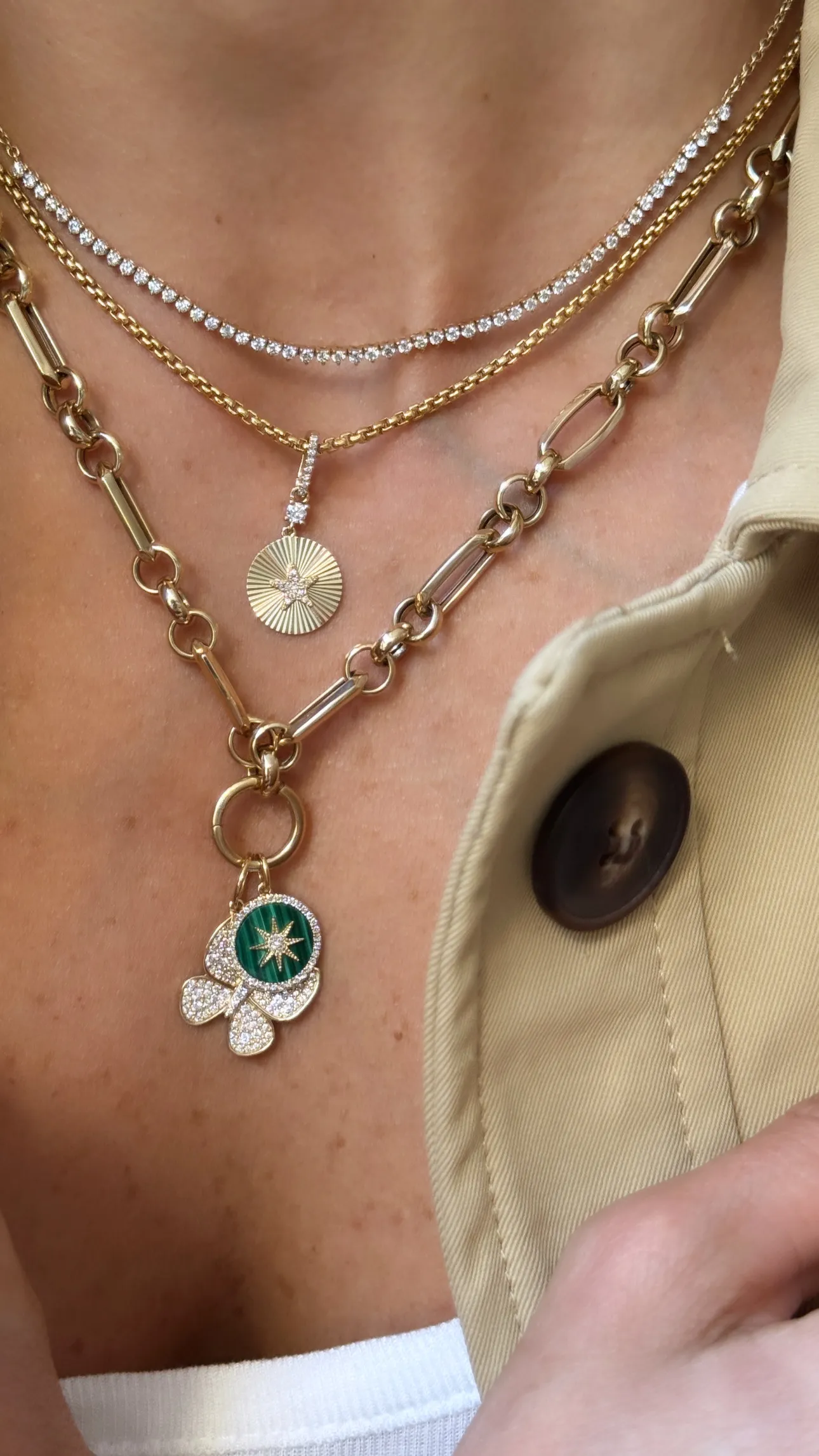 Gold charm necklace featuring textured and decorative pendants, showcasing unique jewelry design.