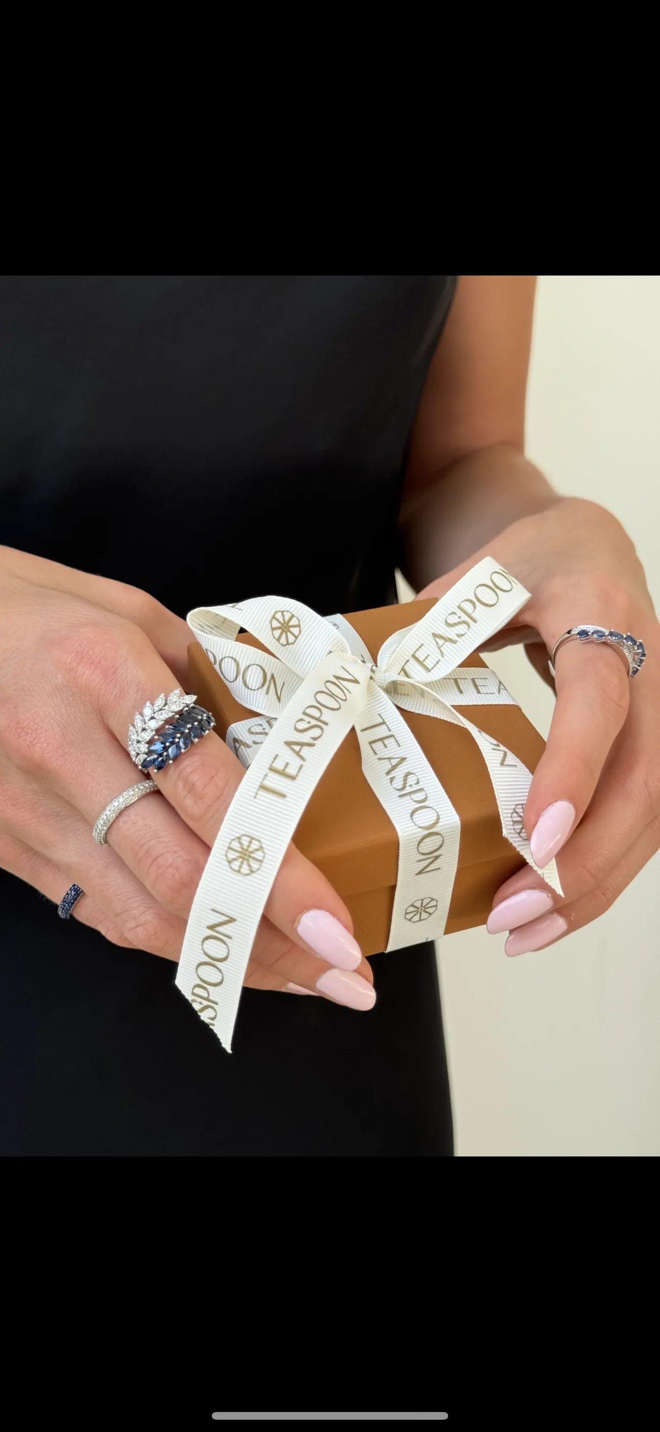 Close-up of a woman wearing layered gold necklaces and rings, showcasing elegant jewelry.