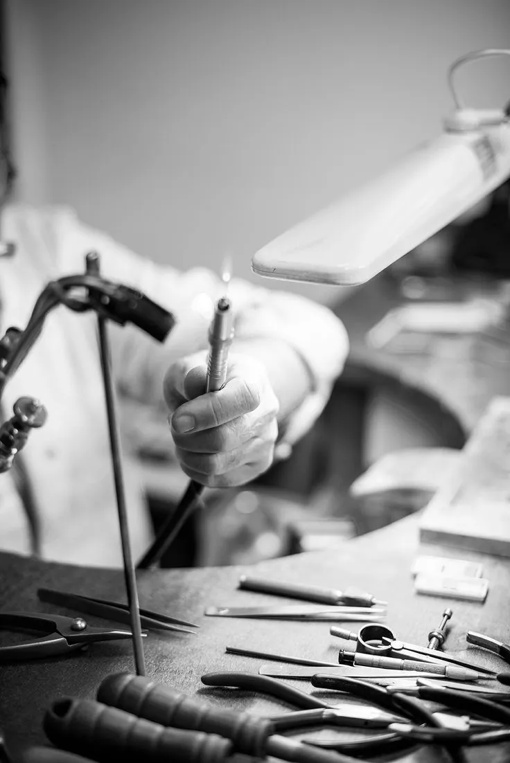 Close-up of a woman’s ear with a silver hoop earring, hand gently touching her hair.