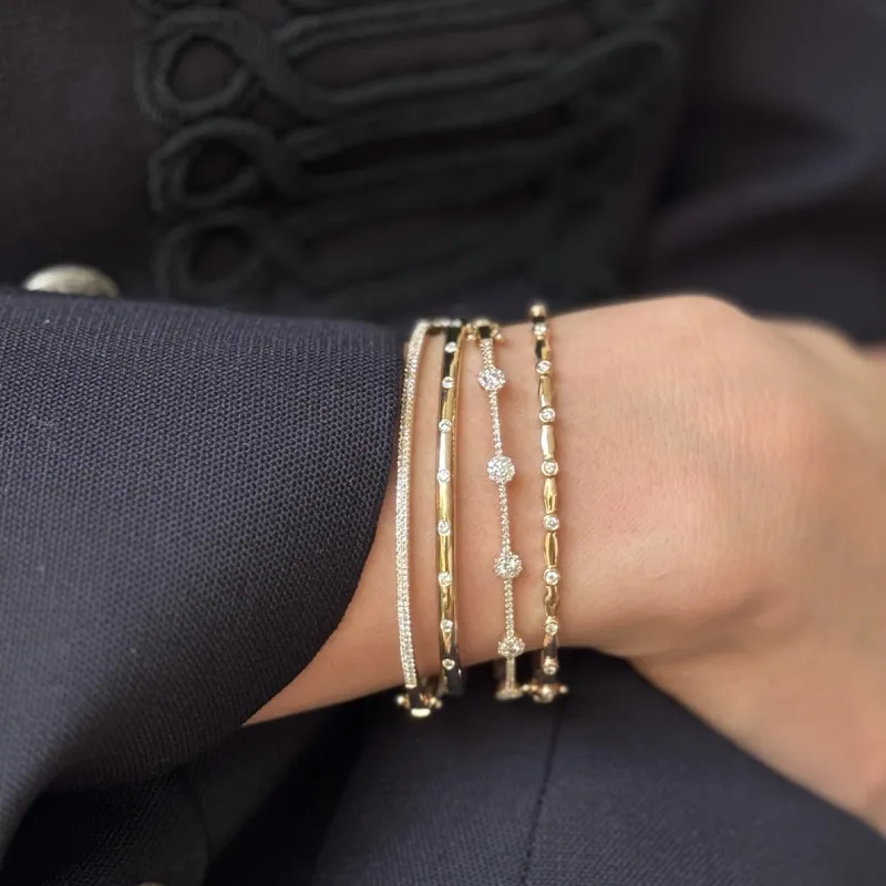 Elegant gold and diamond bracelets stacked on a wrist, showcasing fine jewelry.