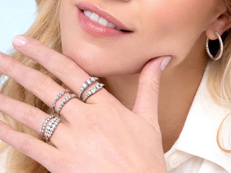 Close-up of a woman showcasing diamond rings and hoop earrings.