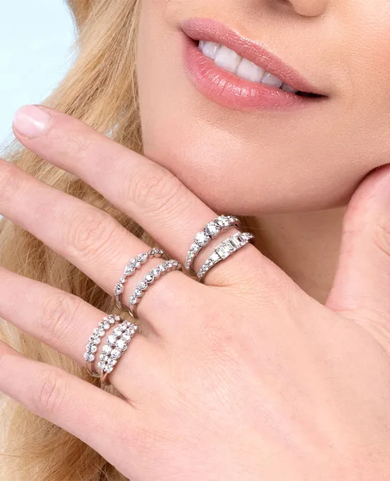Close-up of a woman's hand adorned with multiple sparkling diamond rings, showcasing elegant jewelry.