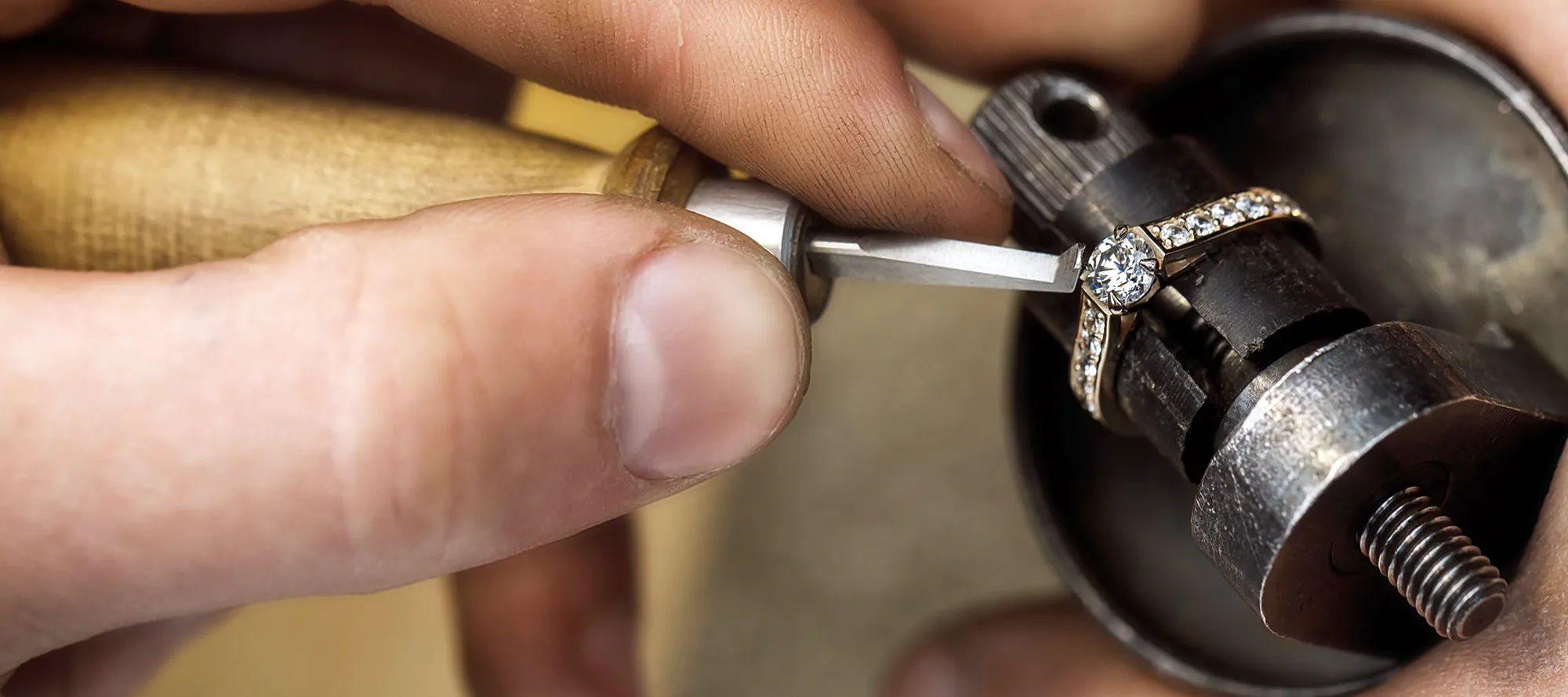 Jeweler working on a ring with tools at a workbench, showcasing craftsmanship.