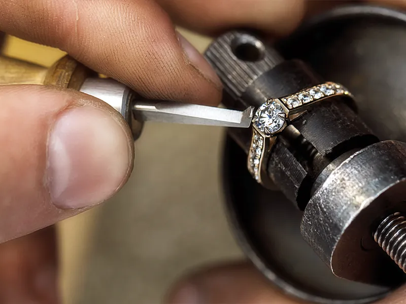 Jeweler working on a ring with tools at a workbench, showcasing craftsmanship.