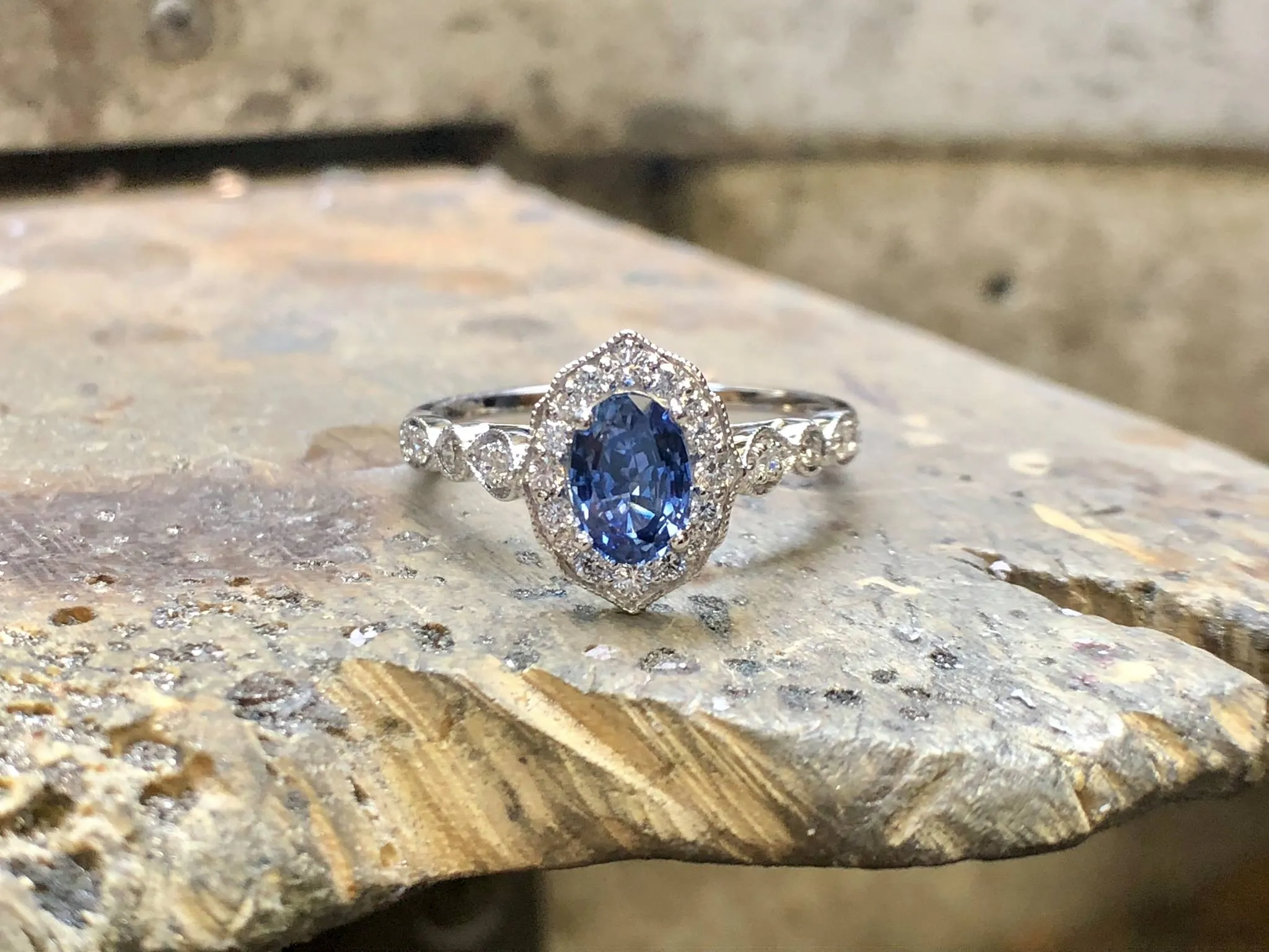 A jeweler using tweezers to place a diamond on a green wax ring model.